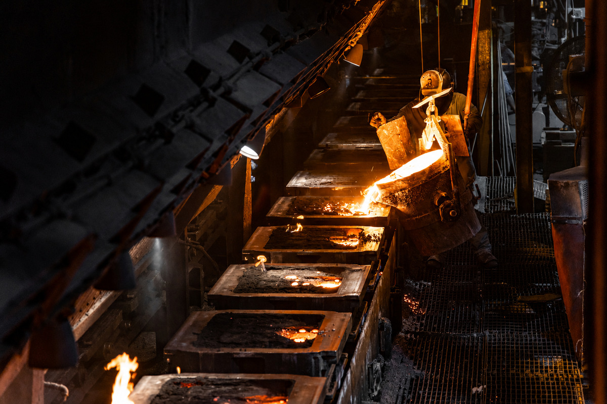 Technician inspecting a cast or forged metal component during production quality control.