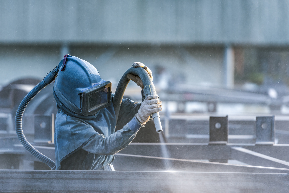 Abrasive blasting removes rust and contaminants from steel before protective coating application.