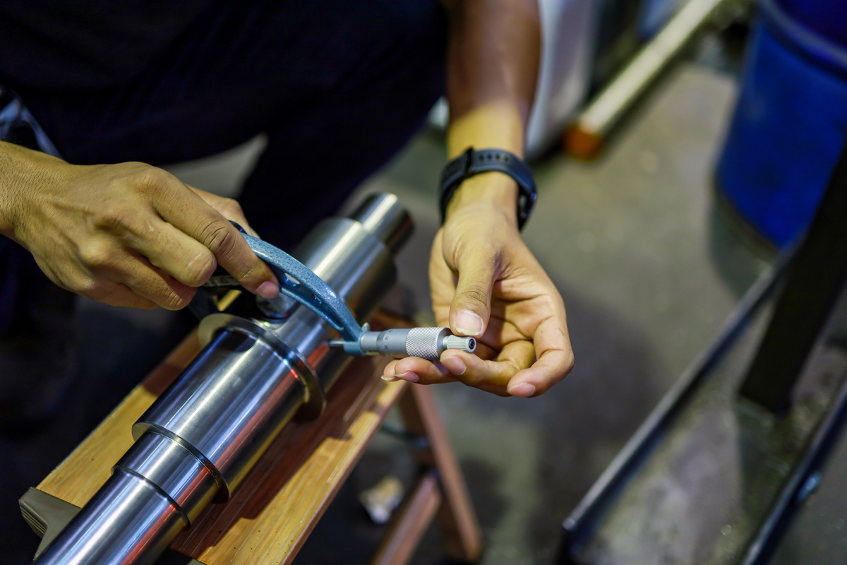 Technician measuring a worn industrial component during teardown to document its as-found condition.