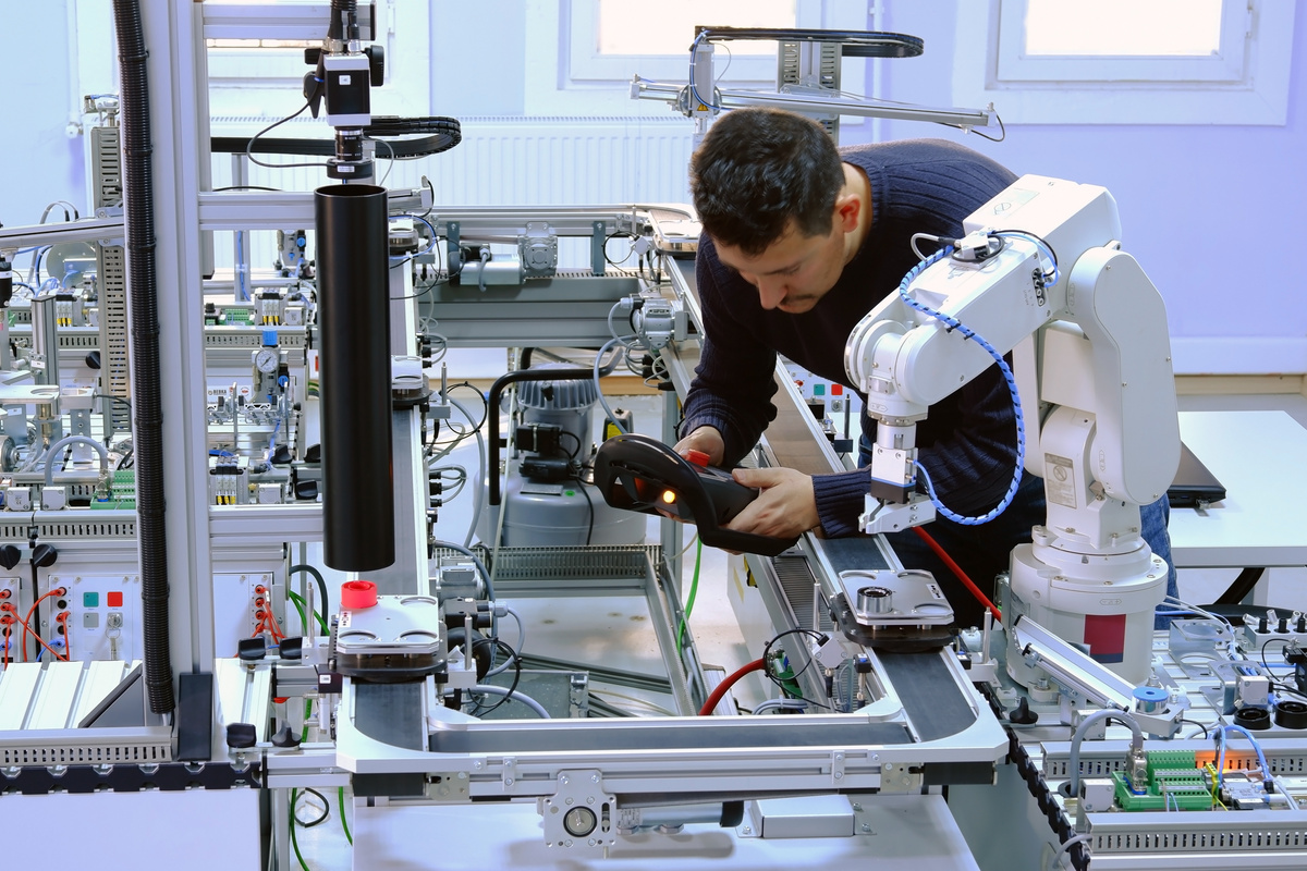 Engineer commissioning and testing an industrial robotic cell during production trials.