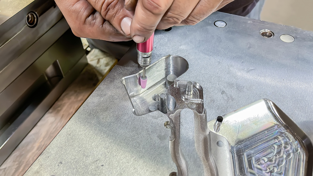 Toolmaker inspecting and maintaining an injection mold used for production parts.