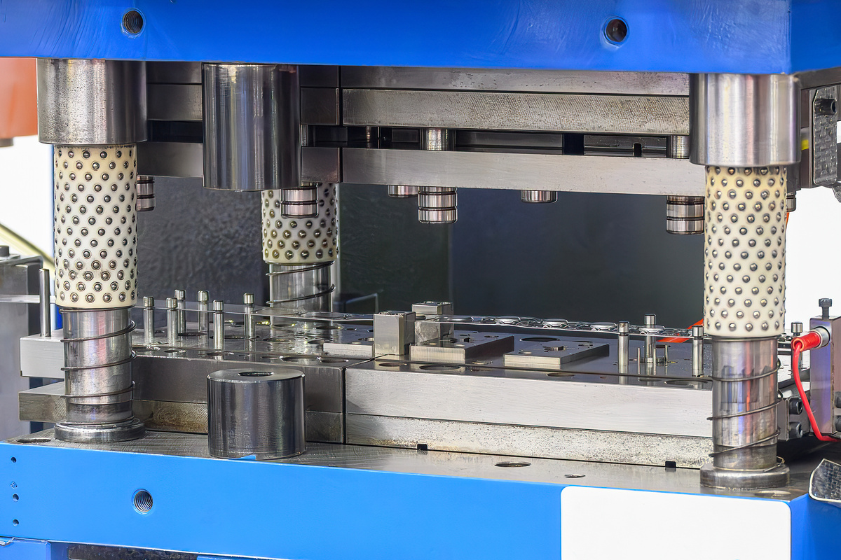 Coil-fed metal stamping press producing parts with progressive tooling.