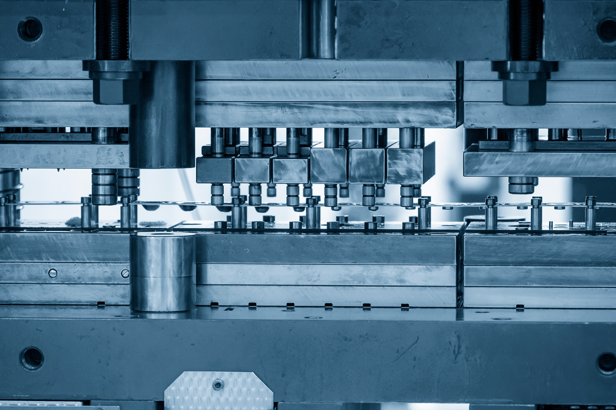 Metal strip showing successive forming stages through a progressive stamping process.