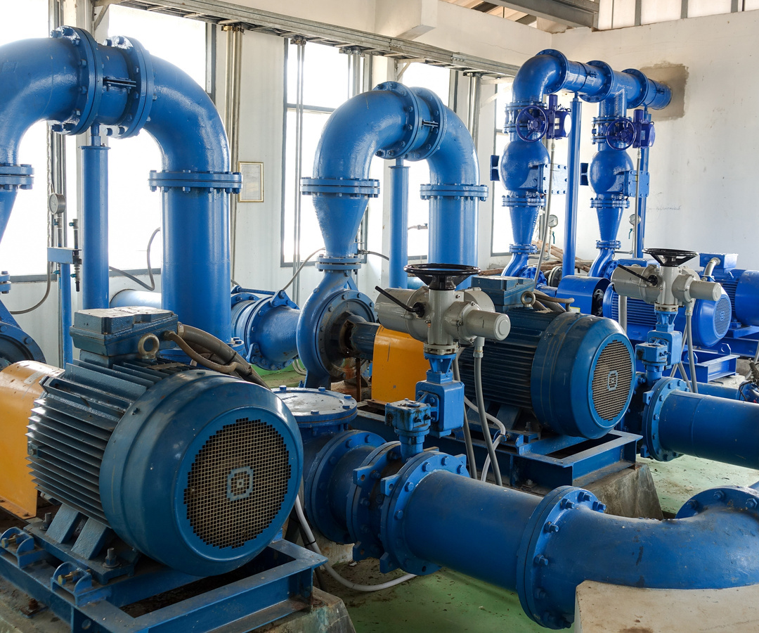 Multiple industrial centrifugal pumps, electric motors, valves, and large-diameter piping installed as part of a fluid pumping system in an industrial facility.