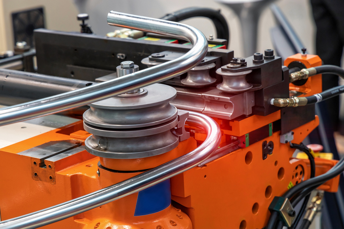 CNC rotary draw bender forming stainless steel tubing around a precision bend die.